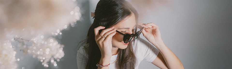 Nahaufnahme einer Frau, die eine Sonnenbrille aufsetzt.