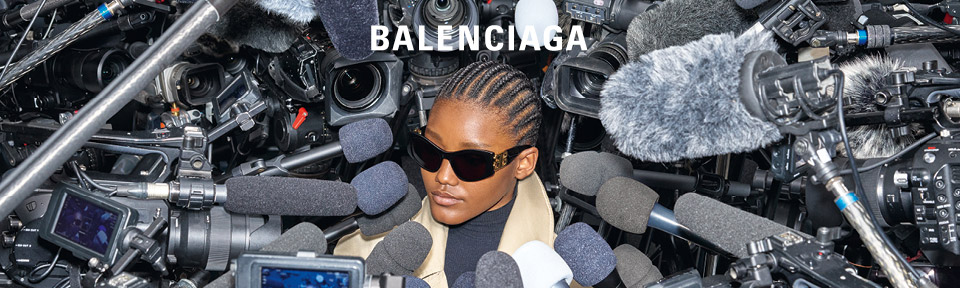 Eine Frau trägt eine Balenciaga Sonnenbrille, während Sie von vielen Mikrofonen umgeben ist.