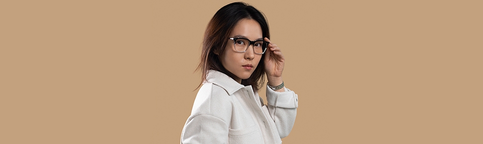 Eine Frau trägt eine Lunor Brille vor einem beigen Hintergrund.