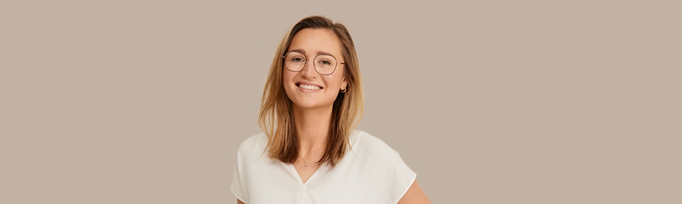 Eine junge Frau trägt eine meineBrille Brille vor einem beigen Hintergrund.