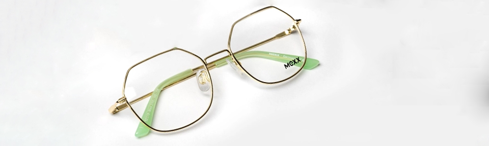 Eine goldene / grüne Mexx Brille liegt auf einem hellen Untergrund.