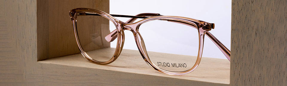 Eine Studio Milano Brille steht in der Mitte vor einem Holzviereck.