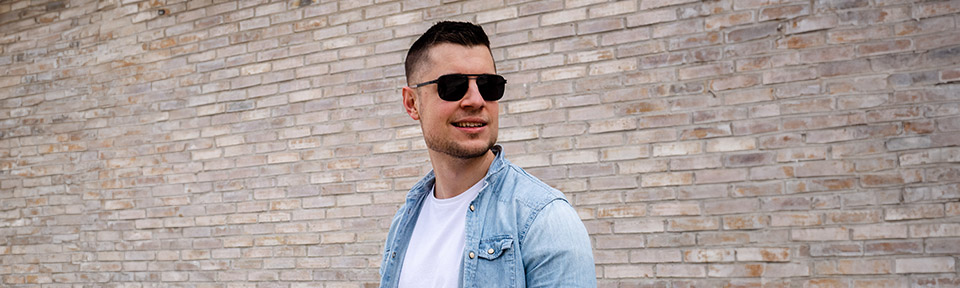 Ein Mann trägt eine Aviator-Sonnenbrille vor einer Gesteinswand.