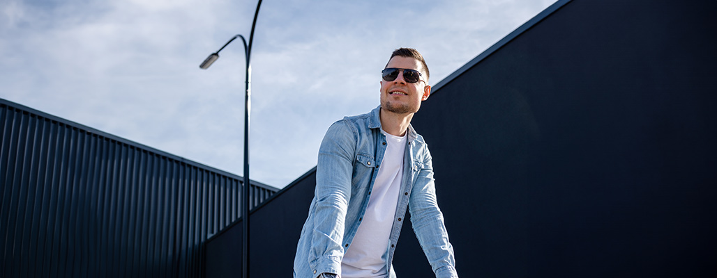 Ein Mann trägt eine Aviator-Sonnenbrille unter blauen Himmel.