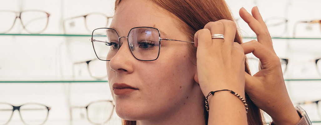 Einer Frau wird die Brille an der Seite des Kopfs angepasst.