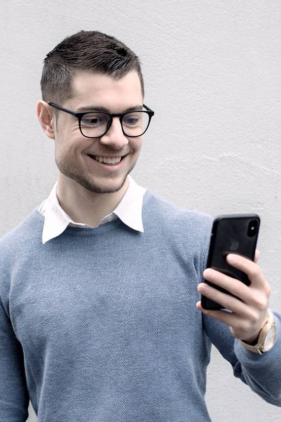 Mann schaut mit Blaulichfilterbrille auf Handy
