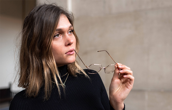 Junge Frau nimmt sechseckige Brille ab