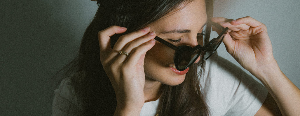 Eine Frau trägt eine schwarze, herzförmige Sonnenbrille für eine Hochzeit.