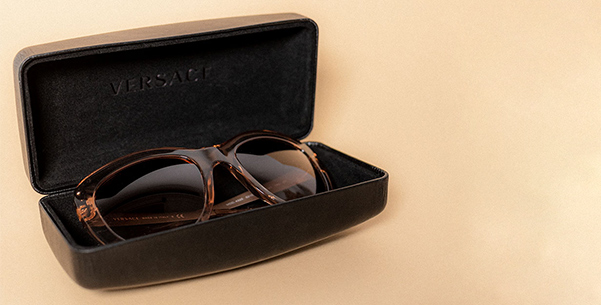 Versace Sonnenbrille in einem geöffneten Etui auf beigem Hintergrund.